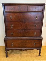 front view of tall highboy dresser showing all drawers and legs on casters