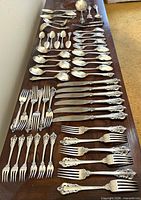 All flatware pieces laid out showing variety of knives, forks, spoons and serving pieces