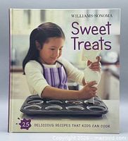 Front cover showing title, brand and child frosting cupcakes