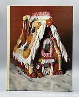Front cover of hardcover cookbook showing gingerbread house image