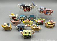 Front view of 16 assorted ceramic teapot figurines