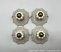Top view of four identical knobs on ornate backplates