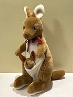 Front angled view of kangaroo plush with joey and ribbon