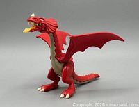 Front three-quarter view of red dragon showing wings, jaw and yellow tongue