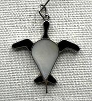 front view of turtle-shaped pendant showing mother-of-pearl inlay and black enamel