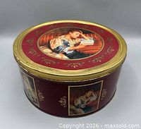 Side view of red round tin with gold rim and artwork panel