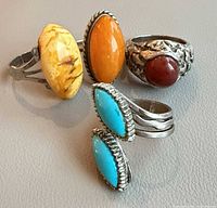 Group shot of four costume rings displaying cabochon colours and settings