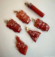 Six red carnelian pendants arranged on surface