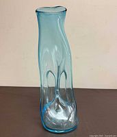 Front view of tall blue free-form glass vase showing overall shape and color