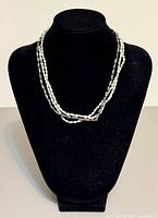 Necklace displayed on black bust showing three strands