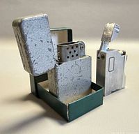 Open flip-top lighter showing case, insert and box alongside Dalton lighter