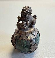 Front view of silver-mounted green stone vessel with foo dog finial