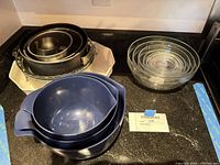 All items grouped: blue plastic bowls, glass bowls, springform pan on white ceramic dish
