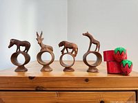 four carved wood animal napkin rings and two painted strawberry rings