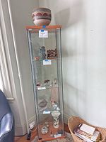 full view of glass curio cabinet with pot on top