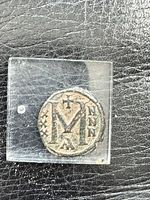 Reverse side with large “M” and flanking legends in plastic holder