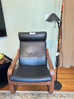 Front view of black leather armchair with bentwood frame and floor lamp