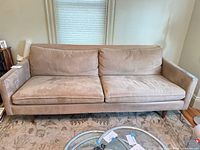Front view of three-seat beige microfiber sofa with tapered legs and two sets of cushions