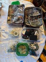 Overview of both tins, plastic containers, bags of beads and spools of cord.
