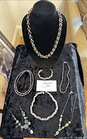 All eight jewelry pieces displayed on black velvet stand and surface