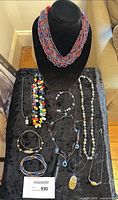 Overview of twelve handmade necklaces displayed on black velvet