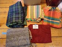 All six folded blankets/throws showing colours, patterns and fringe details