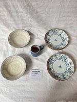 All six ceramic pieces laid out: three plates, two bowls, one mug