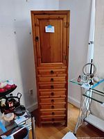 Front view of closed cabinet showing nine drawers and upper door