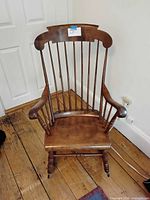 Front view of Windsor-style maple rocking chair showing spindle back, scrolled arms and seat