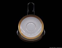 Front view of stacked saucers showing gold encrusted rim and inner pin line