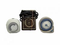 Front view of three mechanical timers—white, brown Brinks with cord, beige