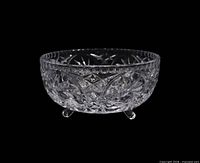 Side view of clear pressed glass bowl showing pinwheel pattern and three feet