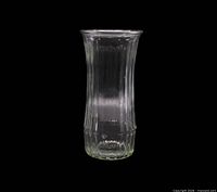 full view of clear ribbed glass vase against black background