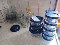 Stack of assorted glass bowls and loose lids on countertop