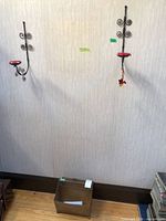 Two wall-mounted sconces and perforated metal magazine holder on wall and floor