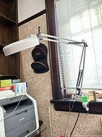 Side view of articulated magnifying lamp clamped to desk