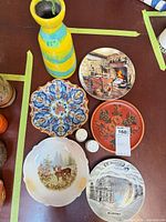 Group shot of five decorative plates, vase, salt and pepper shakers on table