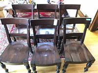 Front view of all six matching dark brown wood dining chairs