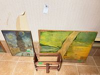 Framed print, wooden planter and green-yellow board leaning against wall