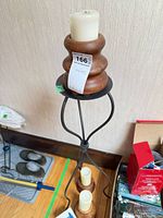 Metal floor candle stand with wooden holder and flicker candle on top, two additional wooden holders with candles below