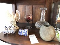 Shelf view showing crystal decanter, iridescent goblet, stone vase, crochet angel, ceramic napkin rings
