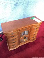 Front view of wood jewelry chest showing drawers and glass door