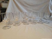 Front view of all twelve clear pressed glass goblets