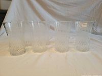 Six of the eight patterned glass tumblers standing upright