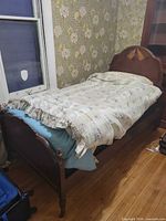 Twin bed frame assembled with bedding showing headboard, side rails and turned legs