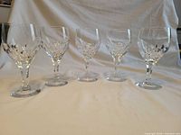 Five cut crystal goblets lined up showing overall quantity and design