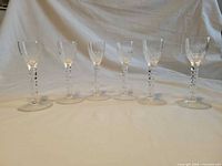 Six matching clear cut crystal wine glasses in a row