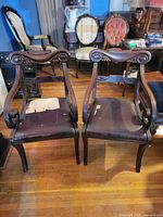 Front view of both mahogany armchairs showing carved backs and seat wear
