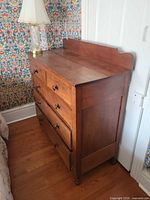 Front and side view of full chest showing four drawers, backsplash and cushion feet