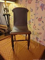 Front view of wooden child's chair showing leather seat/back and turned legs